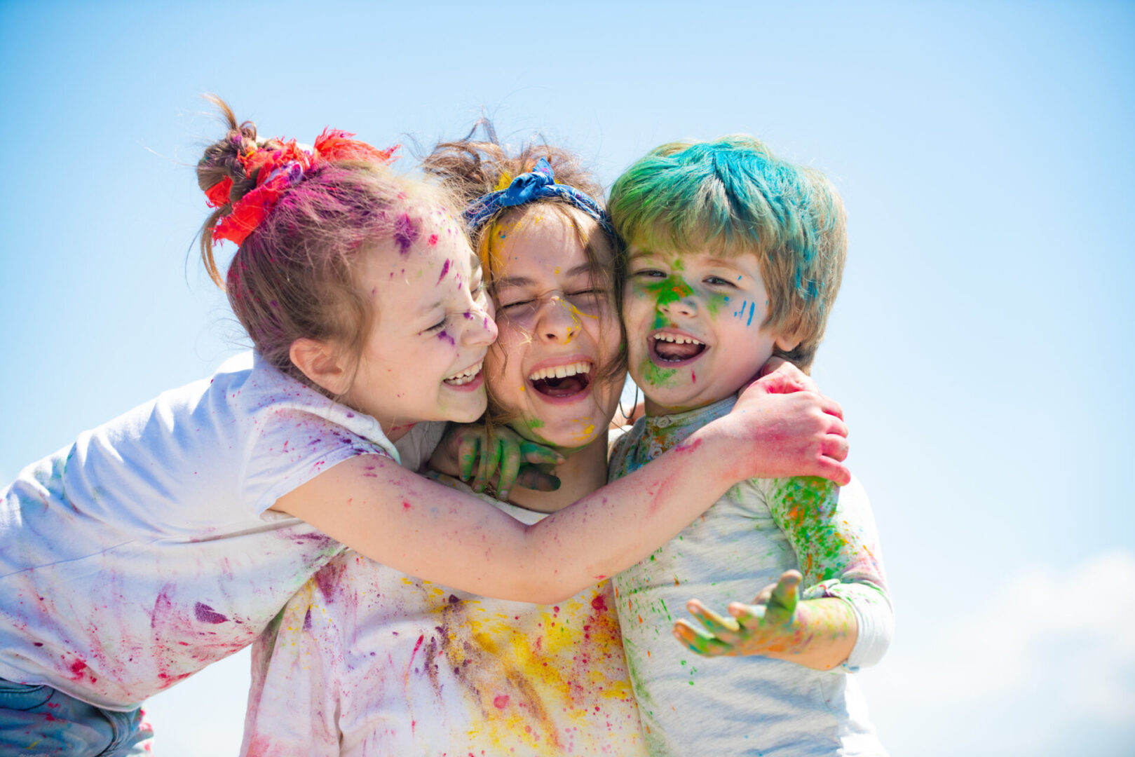 Three children with vibrant paint on their faces showcasing the qualities of the Aries sign.