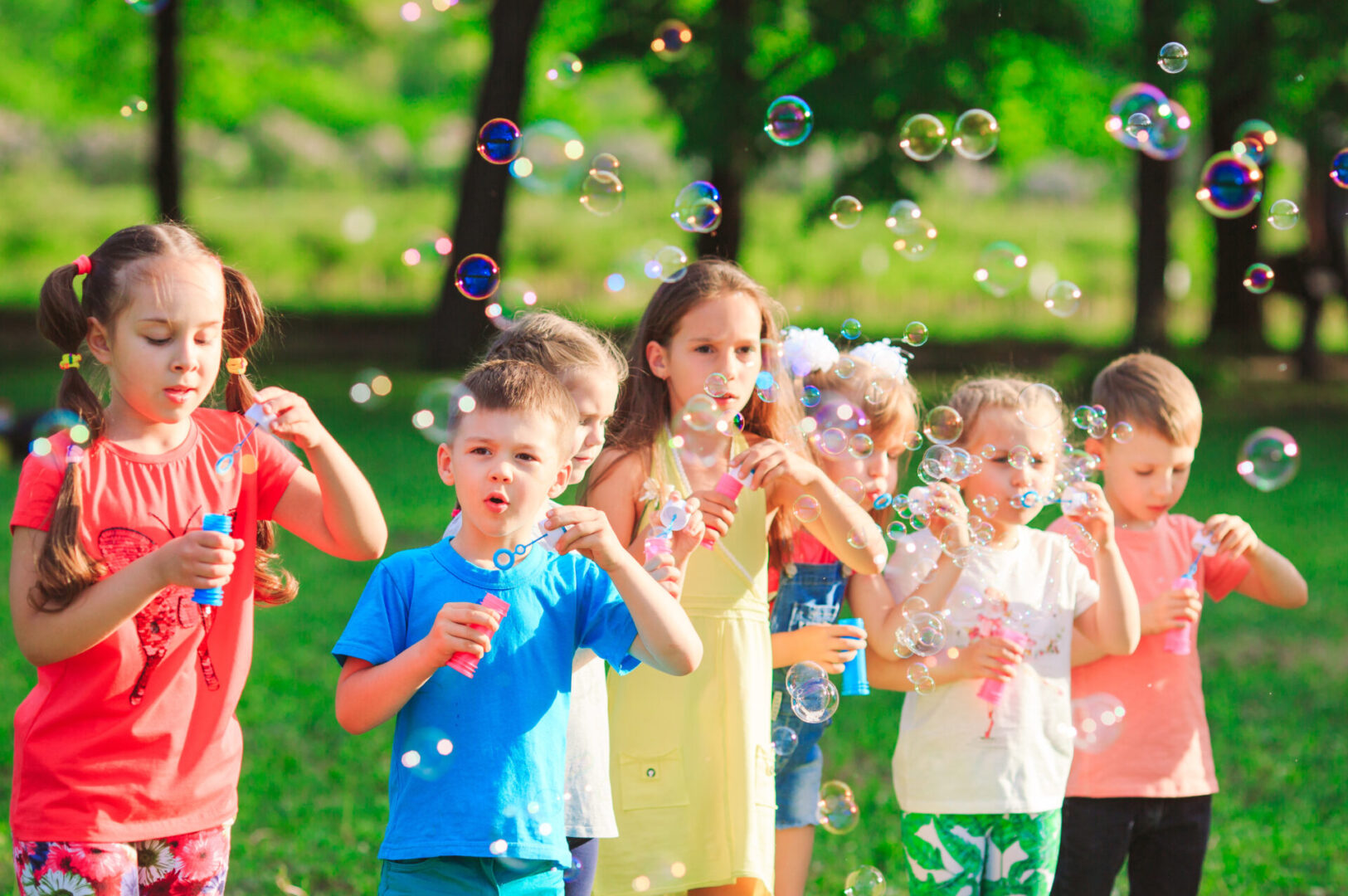 Children playing with soap bubbles in a park, displaying the joyful and playful qualities of the Leo Sign.