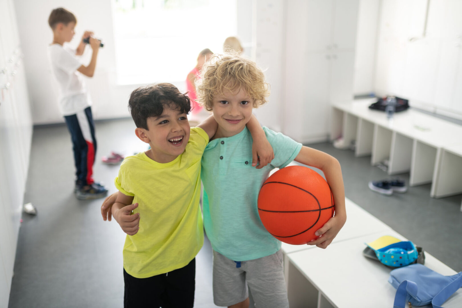 Two boys exhibiting the qualities of the Sagittarius Sign, holding basketballs in a locker room.