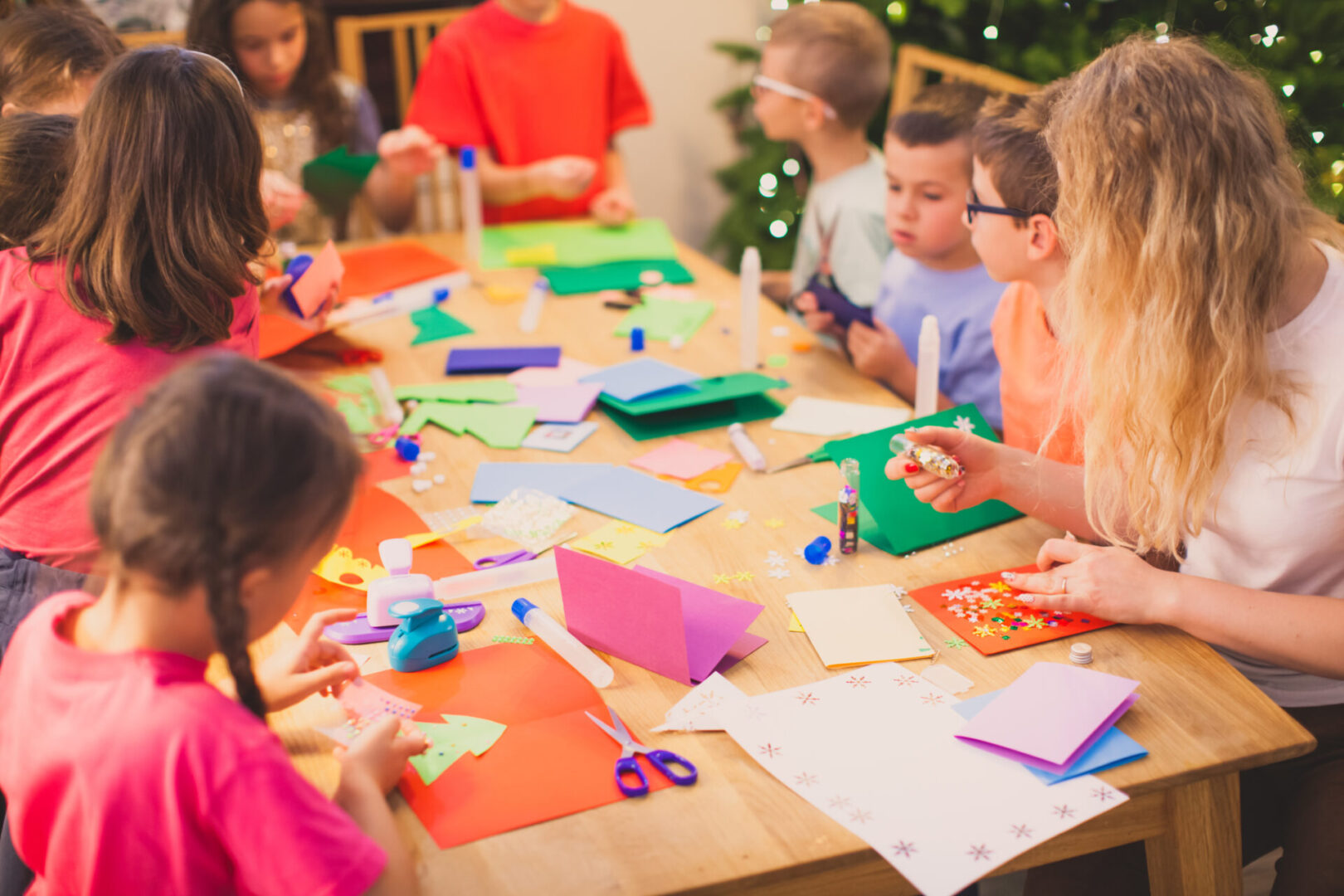 A group of children are making paper crafts at a table, demonstrating their creativity and dexterity.